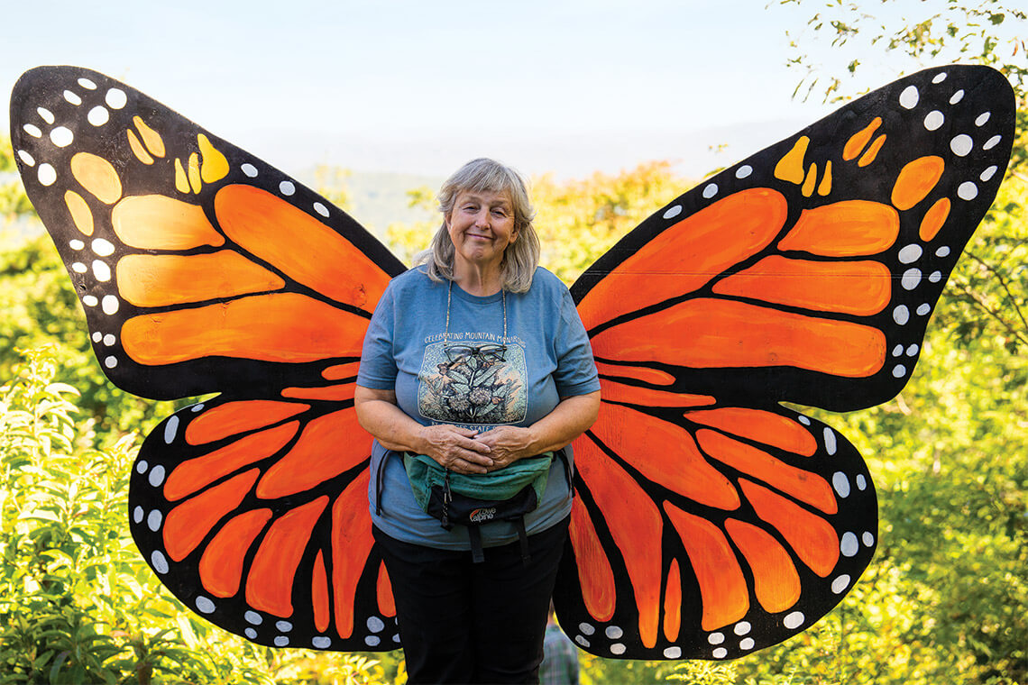 Ina Warren stands in front of giant monarch butterfly wings at the Mountain Monarch Festival