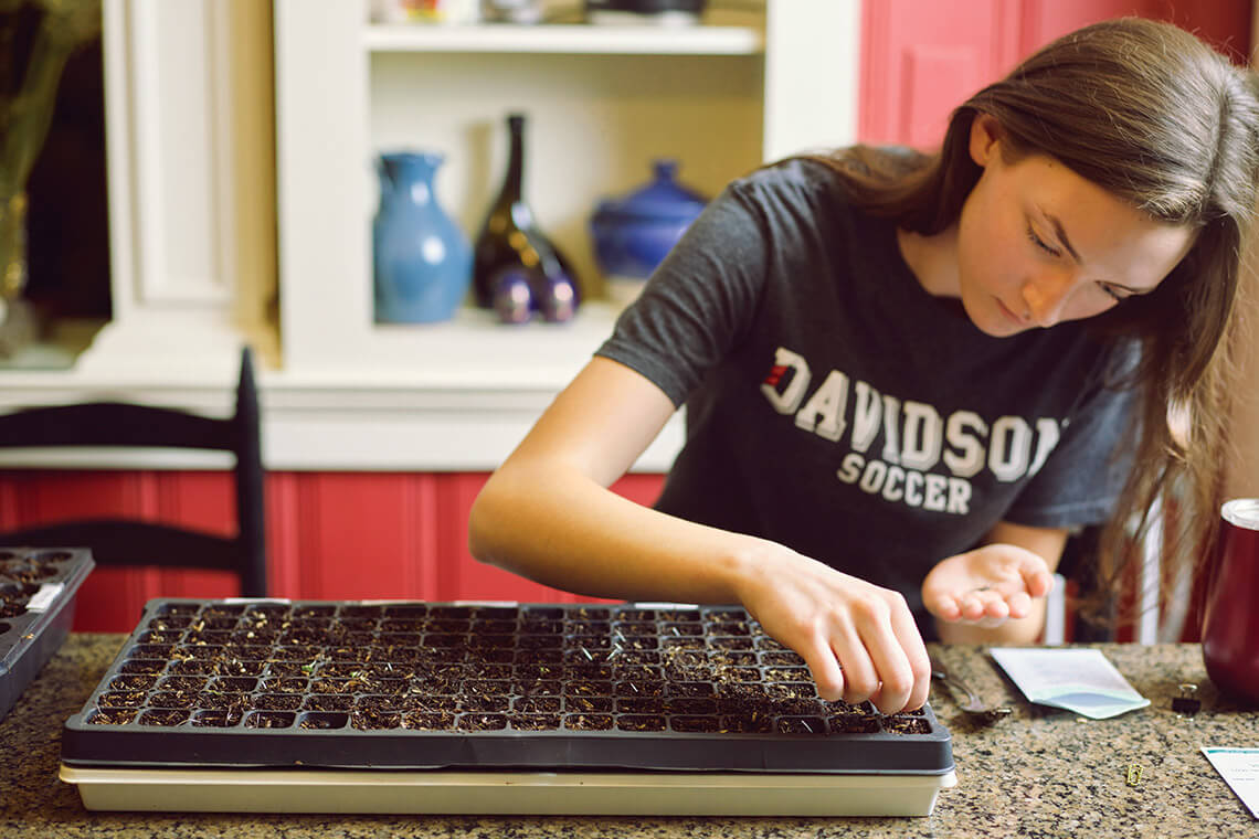 Nora Brantley places lettuce seeds in a starter tray