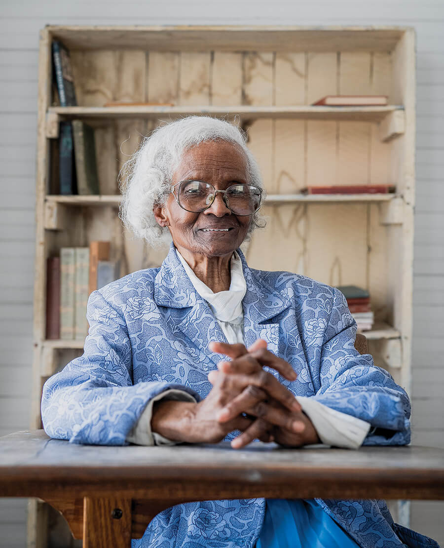 Tammer Mae Armstrong sits at a desk inside the Jarvisburg Colored School 