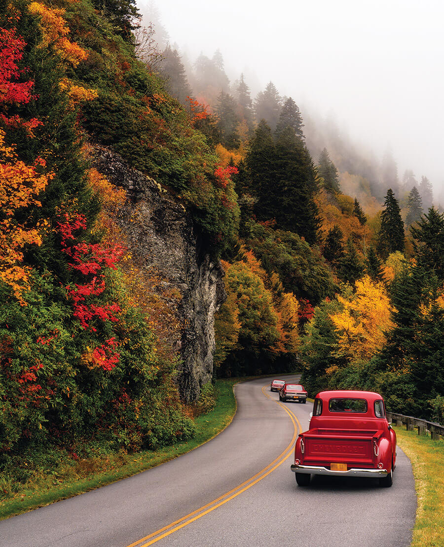 Red cars drive along the Blue Ridge Parkway in the fall