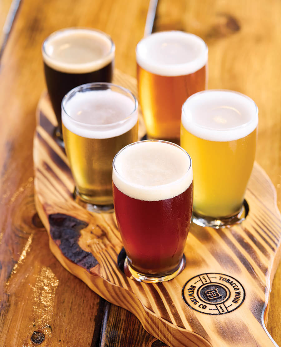 Flight of beers on a board shaped like a tobacco leaf