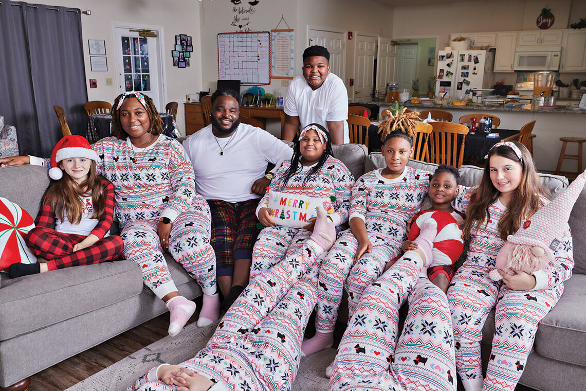 Elizabeth Huff, Octavia and Justin Pickett, Jacetyn Pickett (standing), Rikyjah Eubanks, Asya Brandon, Addisyn Pickett, and Jaycee Briggs all wearing Christmas pajamas