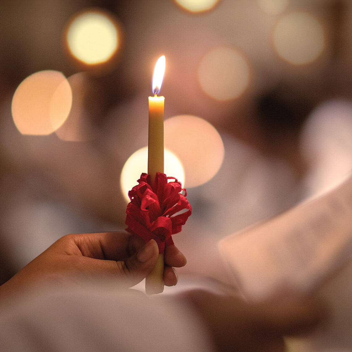 A hand holding a lit candle