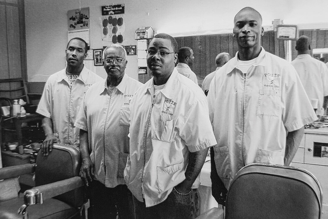 Black-and-white photo of previous barbers at Potts Barber Shop, including Chad Hill, Mickey Potts, Marty Henderson, and Mark Muldrow