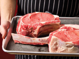 Zev Flinchum holds tray of tomahawk rib eyes