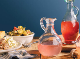 Assorted jars of vinegars on a table with barbecue and vegetables