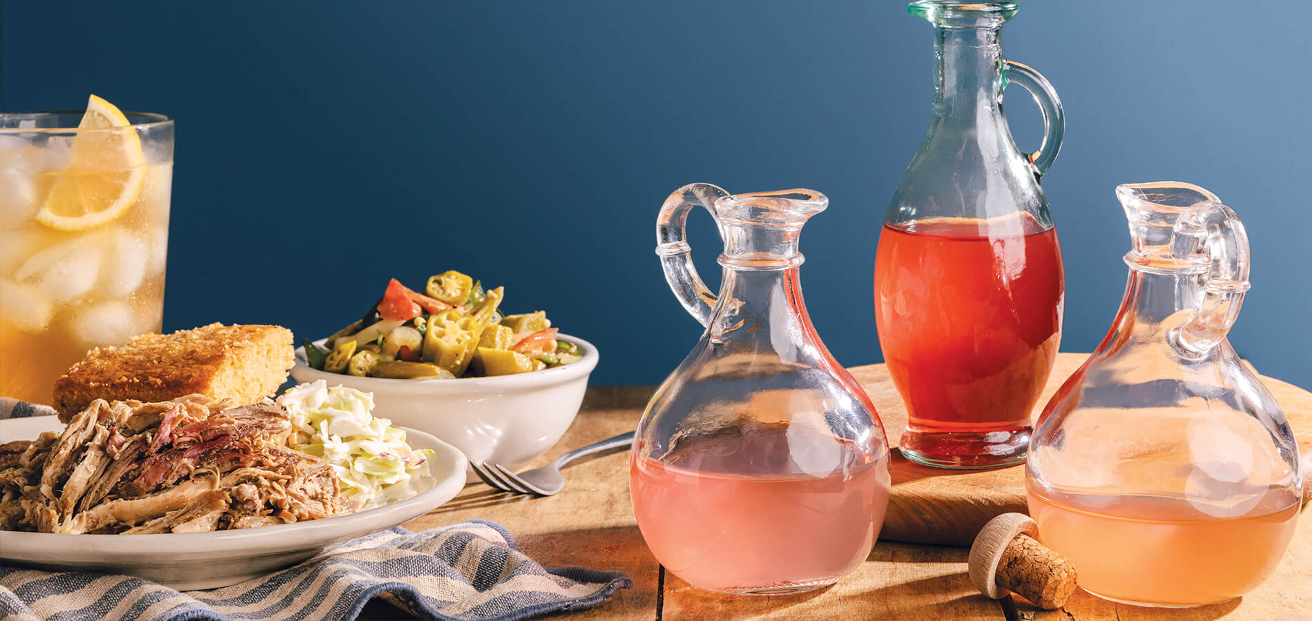 Assorted jars of vinegars on a table with barbecue and vegetables