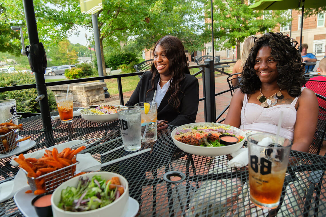 Diners eat lunch on the patio at Me's Burgers & Brews