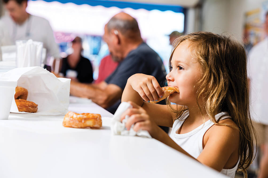 Little girl bites into a doughnut at Britt's