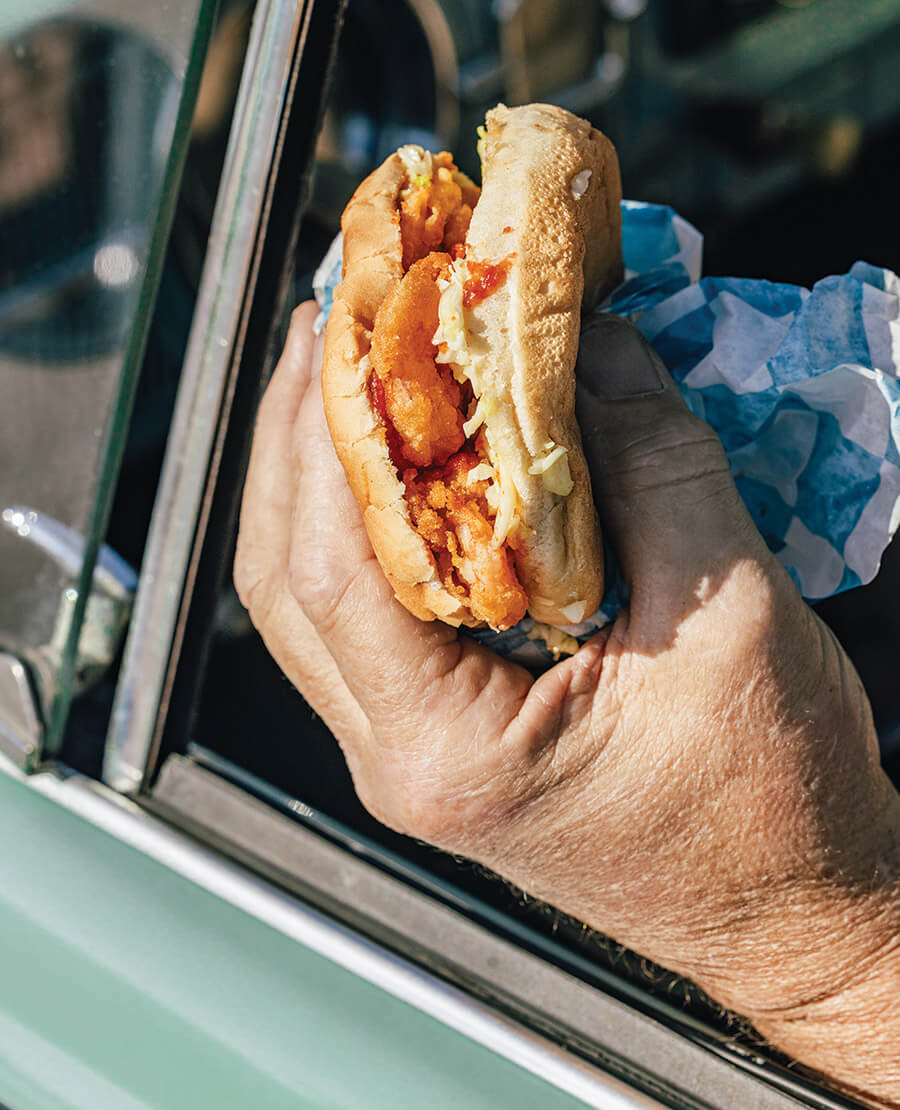 Hands holding a shrimpburger in a car