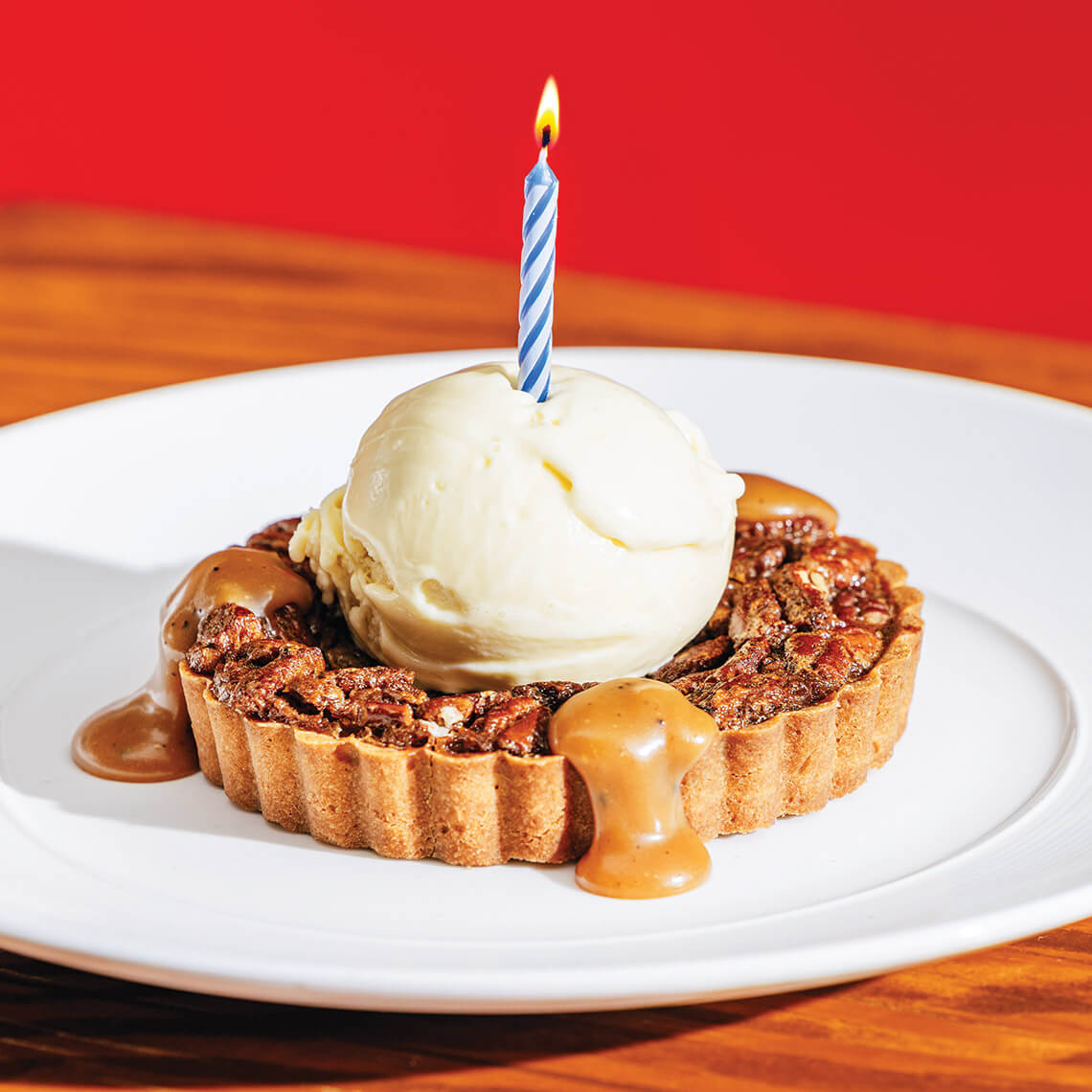 Pecan pie topped with ice cream and a candle
