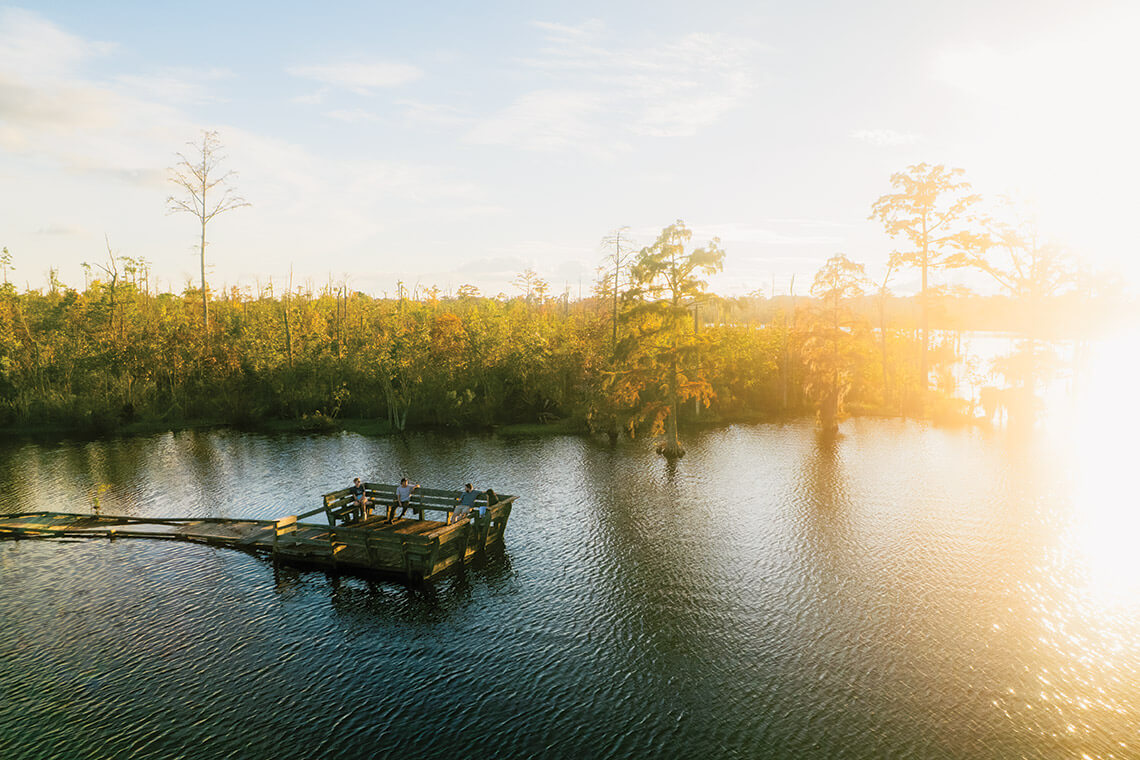 People sitting on the Scuppernong River Interpretative Boardwalk in Manteo