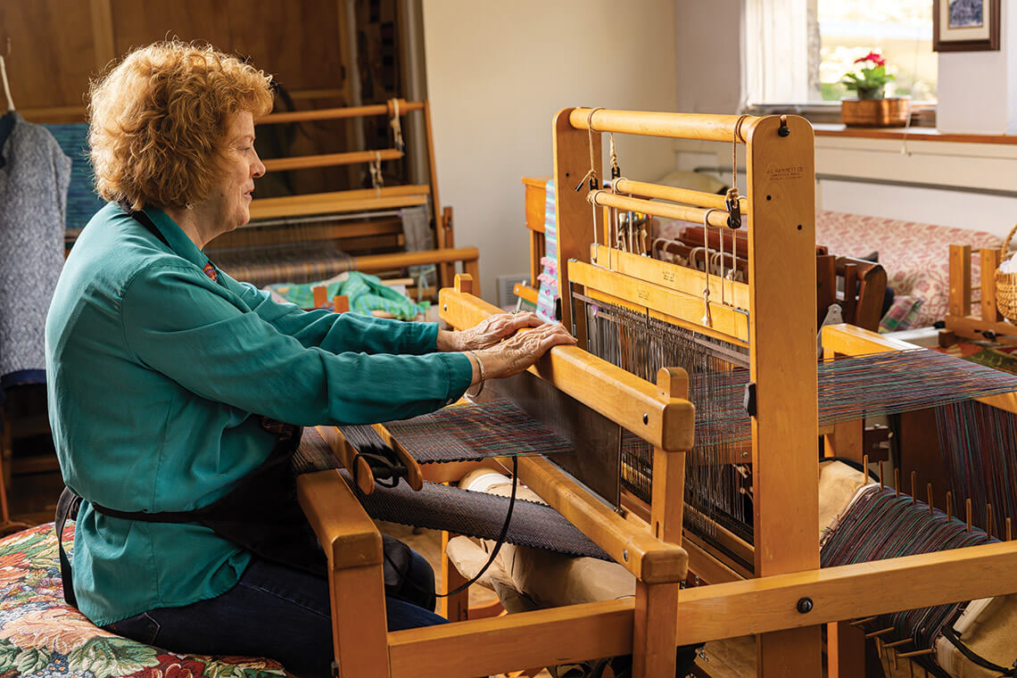 Bouchonnet operates the shuttle to weave fabric in her studio
