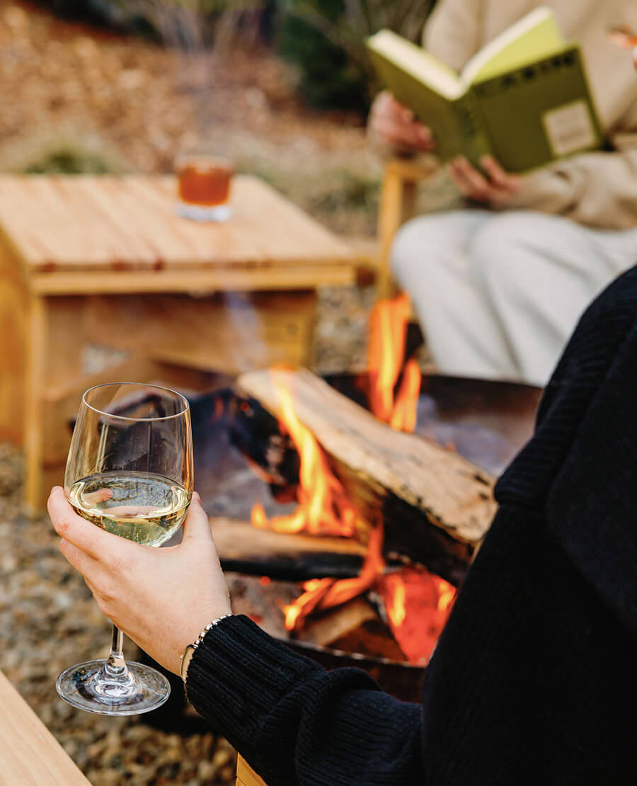 Woman with wine by an outdoor firepit