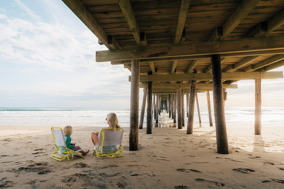 Mom and child in beach chairs at Nags Head Fishing Pier