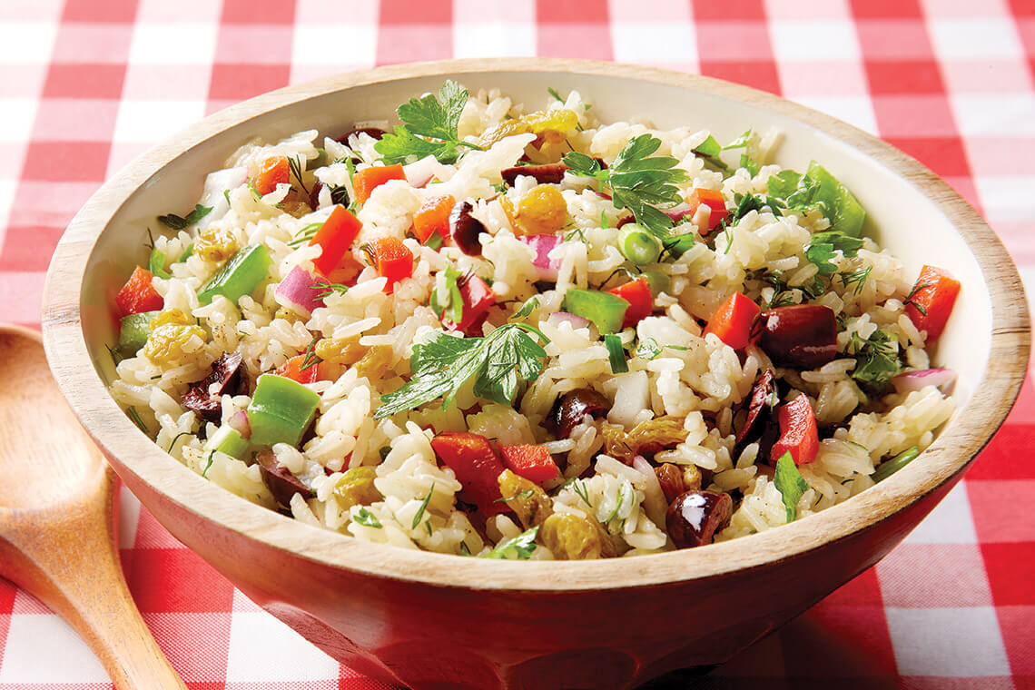 A bowl of rice and vegetable salad with fresh herbs.