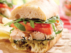 Chicken pesto and tomato sandwich on a picnic table