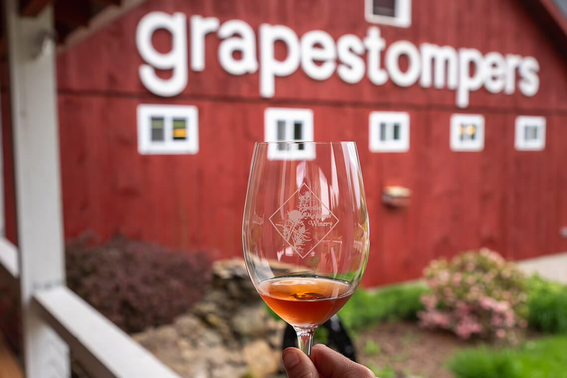 Glass of wine next to a barn at Thistle Meadow Winery