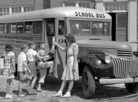 Black and white photo of children boarding a school bus