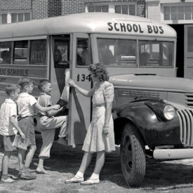 Black and white photo of children boarding a school bus
