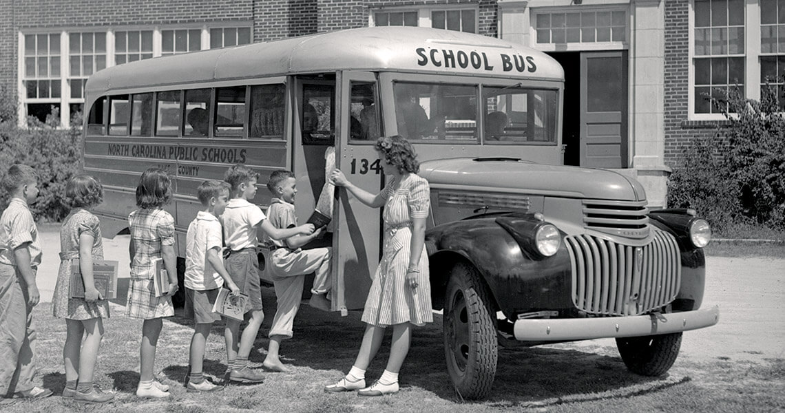 Black and white photo of children boarding a school bus