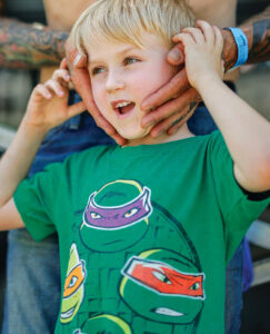 Child with father's hands over his ears to muffle the noise