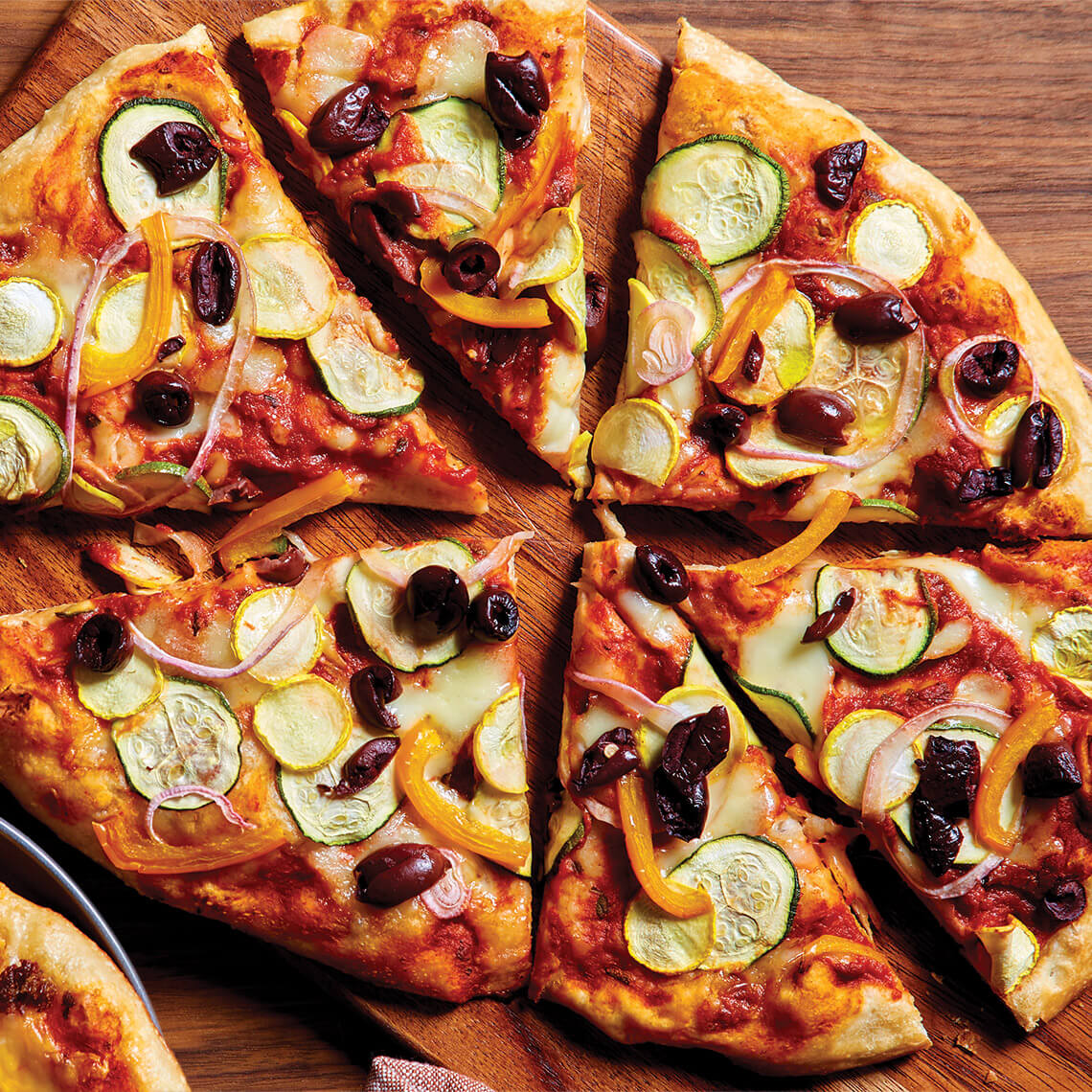 Pizza topped with zucchini, peppers, and olives