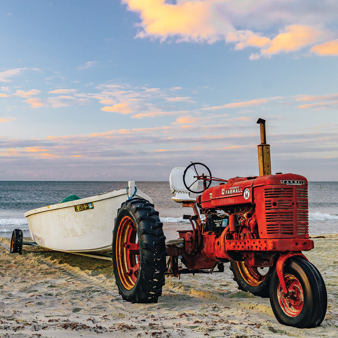 A Farmall tractor towing a wooden boat in Salter Path 