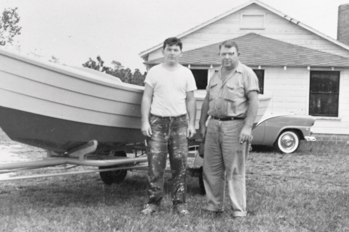 T.N. "Sims" Simmons with his son next to one of his skiffs