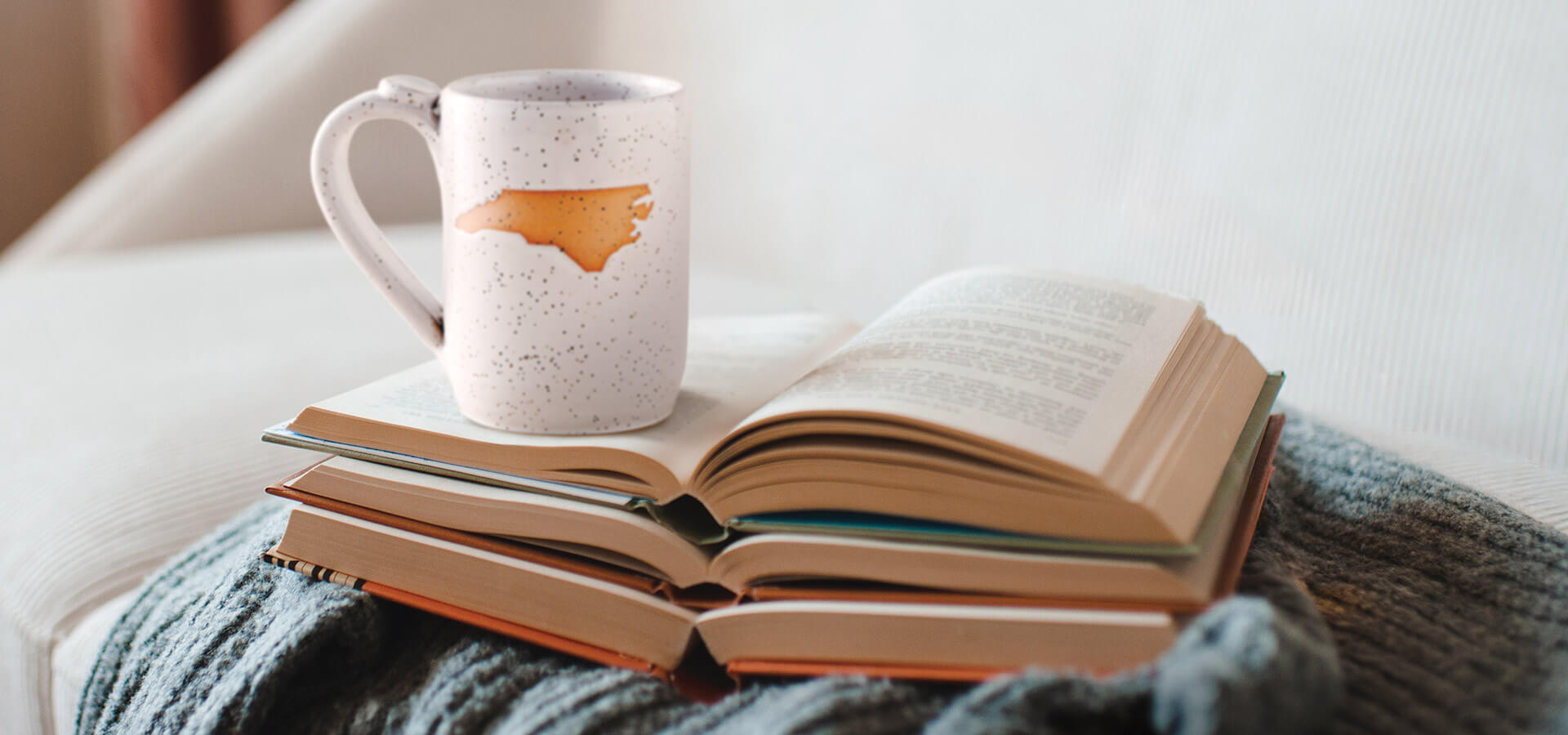Open books and a mug with the state of North Carolina on it