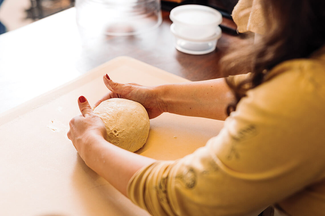 Student shapes dough into boule