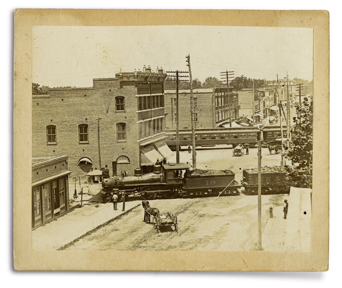 Horse-drawn carriage and freight train on Elm Street in Greensboro