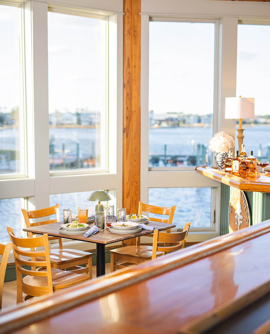 Table set for dinner and window overlooking the water at Salt & Cypress