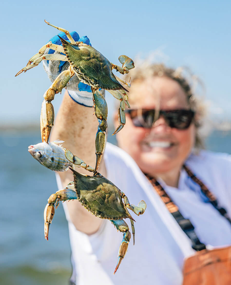 Basnight holds two blue crabs clinging to a fish