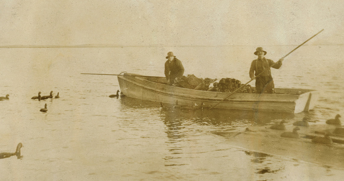 Black and white photo of hunters setting out duck decoys