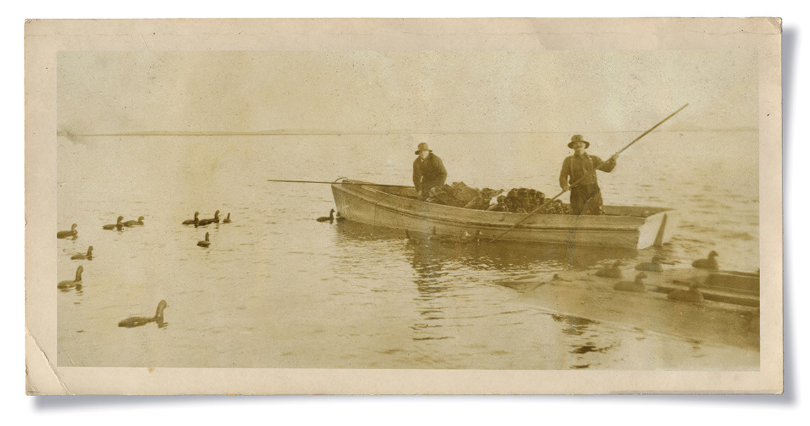 Black and white photo of boaters setting out decoys in Currituck Sound