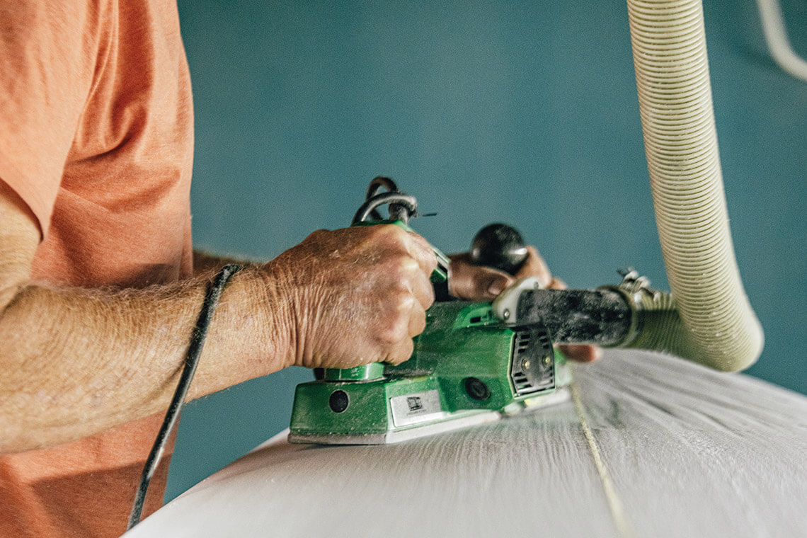 Scott Busbey smooths a board with a planer