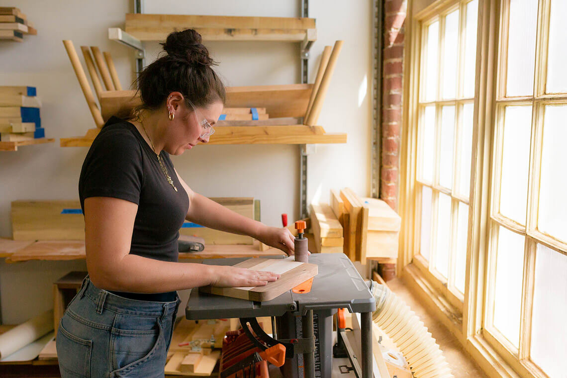 Woman sands cutting board at Sawtooth School for Visual Art