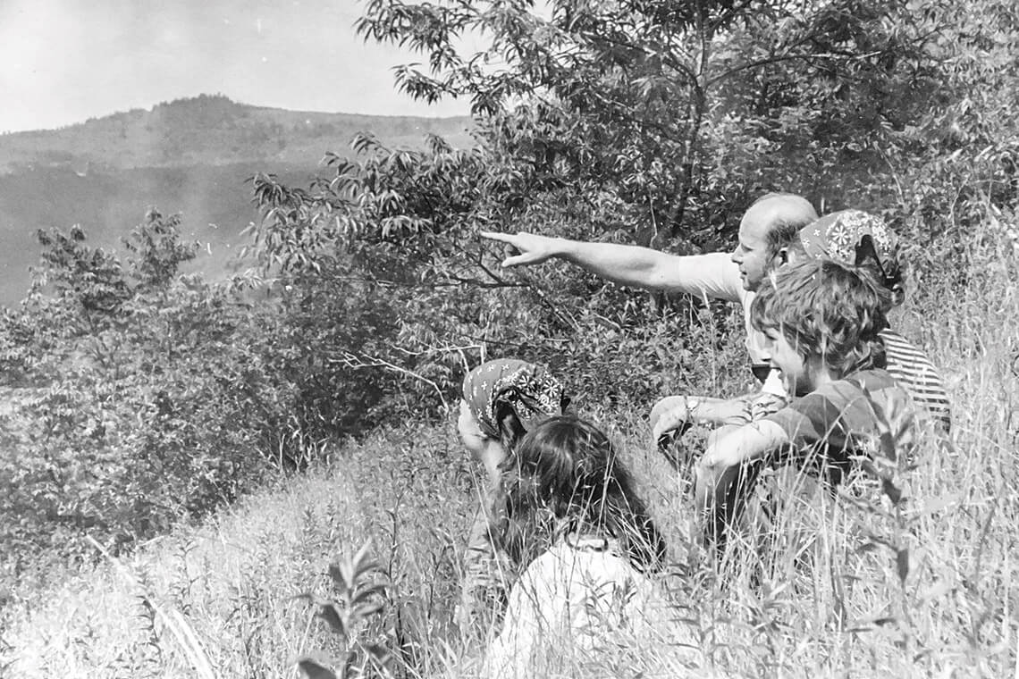 1960s photo of Bill Waggoner pointing landmarks in the mountains to campers