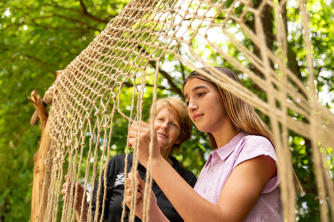 Child and educator weave fishing net at Jamestown Settlement
